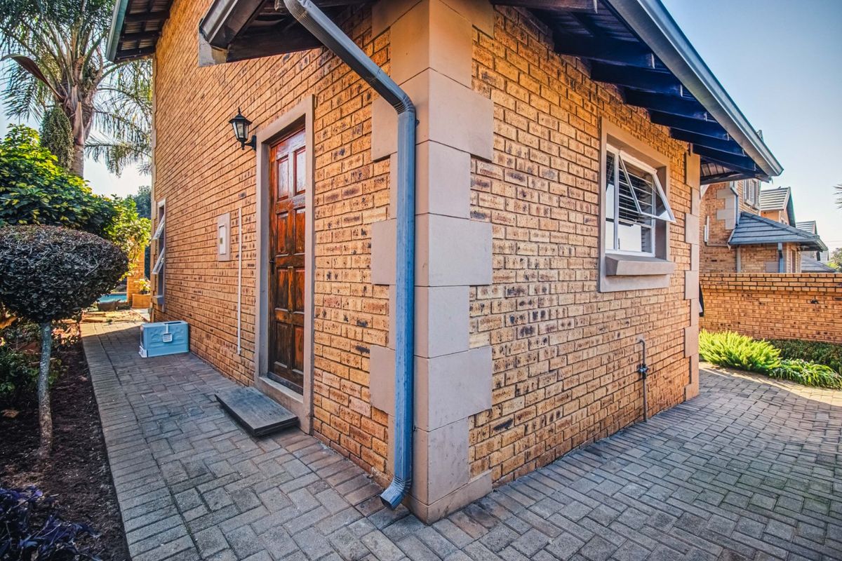 A side view of the property featuring face brick exterior walls, a paved walkway, and a timber entrance door.