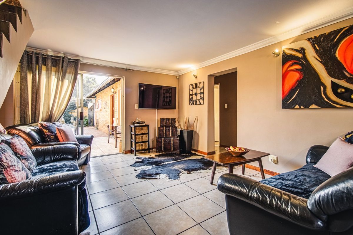 A comfortable living room featuring tiled flooring, cove cornicing, and a sliding glass door providing direct access to the outdoor patio area.
