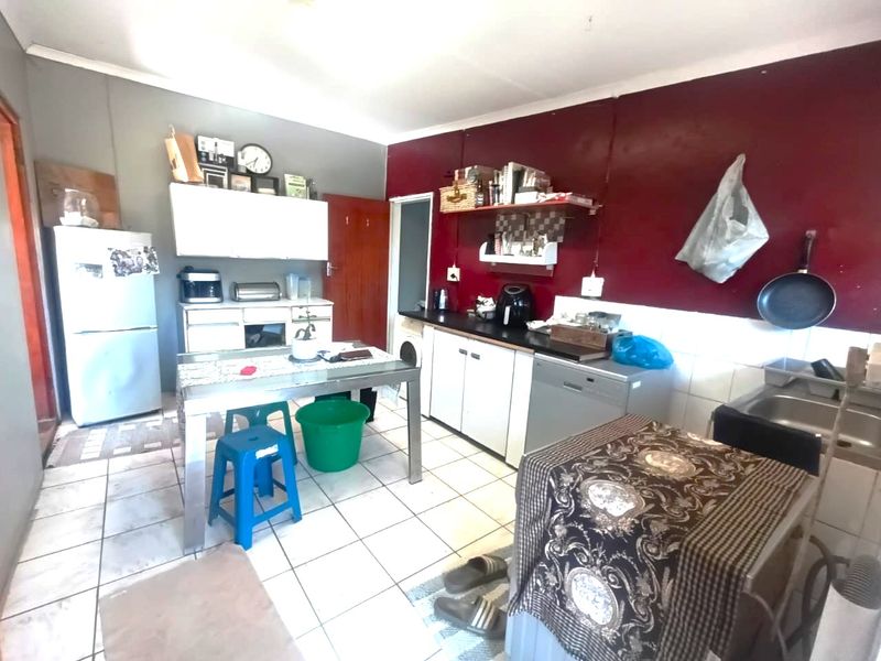 A functional kitchen featuring tiled flooring, built-in cabinetry, and a stainless steel sink, offering potential for modernization and aesthetic updates.