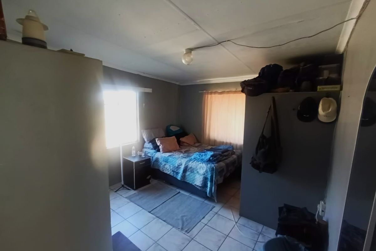 A bedroom featuring tiled flooring and a simple ceiling light fixture, requiring some cosmetic attention to the ceiling.