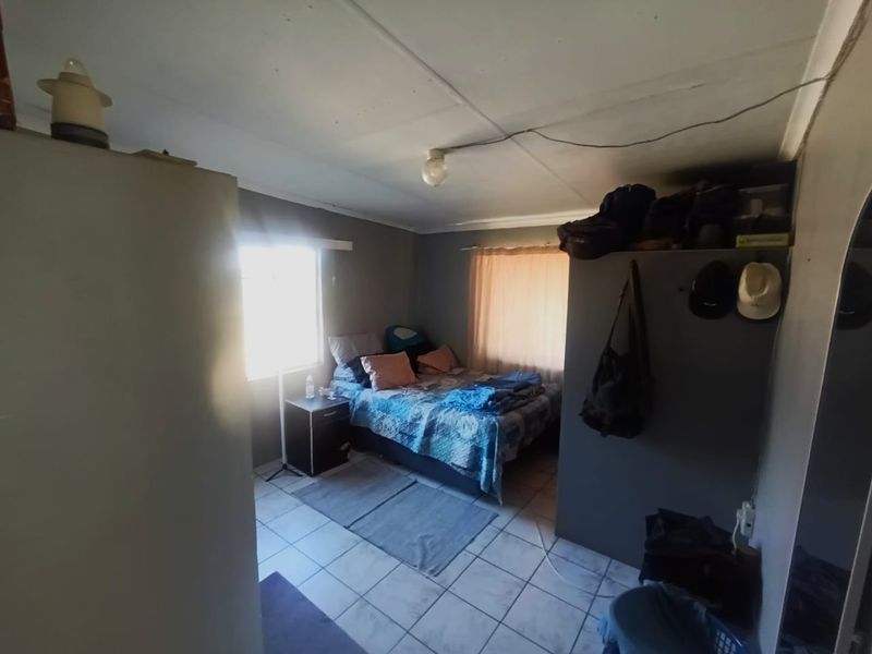 A bedroom featuring tiled flooring and a simple ceiling light fixture, requiring some cosmetic attention to the ceiling.