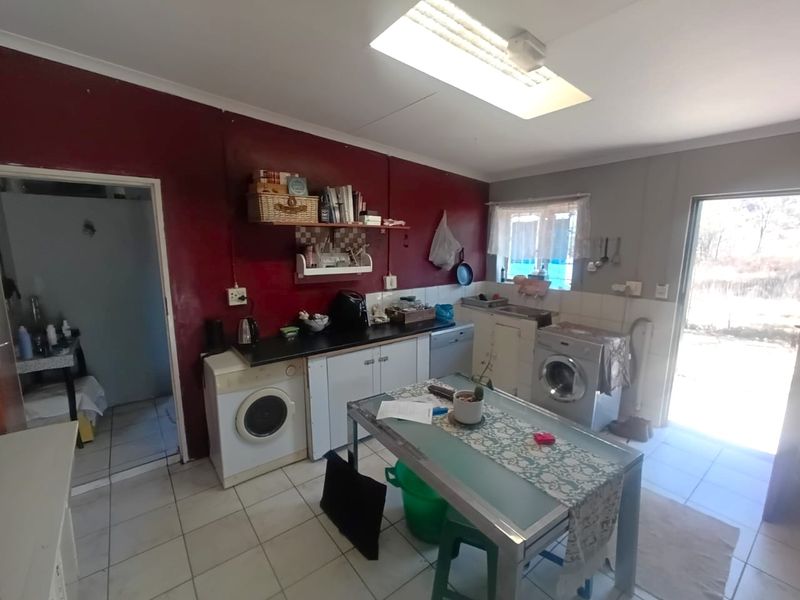 A functional kitchen area featuring tiled flooring, built-in cabinetry, and direct access to an outdoor space, offering potential for modernization and aesthetic updates.