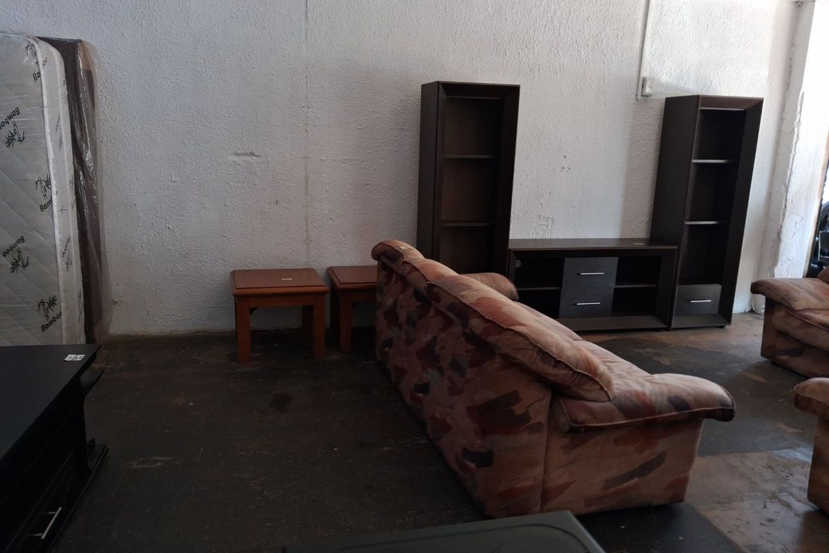 A commercial space featuring textured walls and dark concrete flooring, currently utilized as a furniture display area.