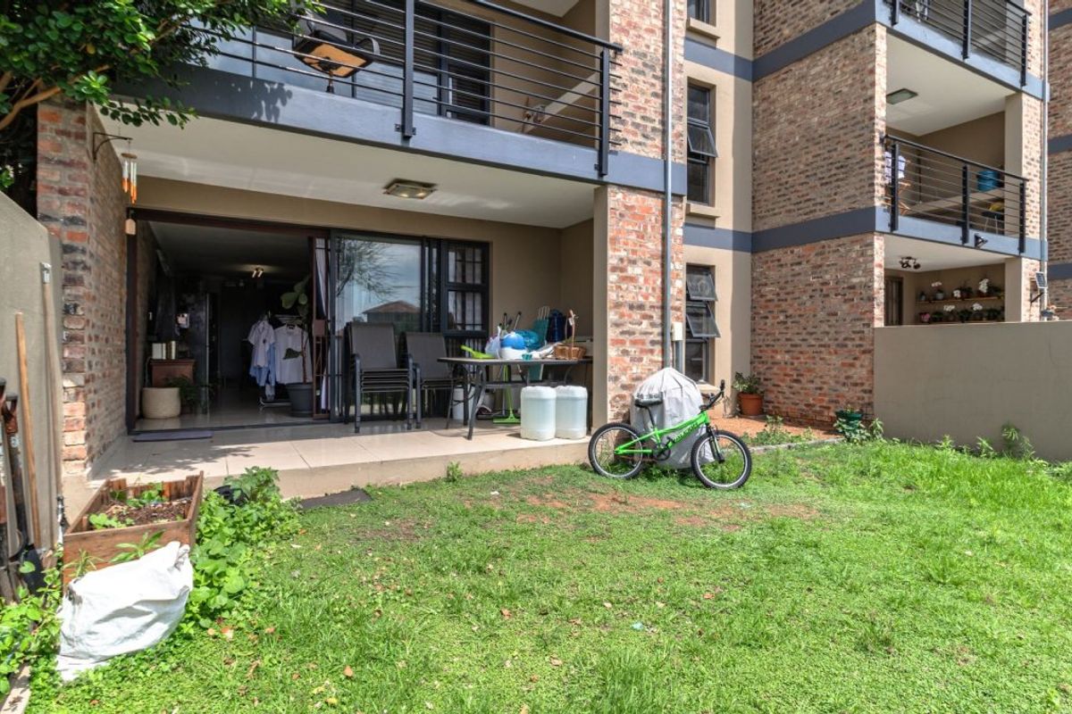 Ground floor apartment featuring a tiled patio area leading out to a private garden space with brick facade and balcony above.