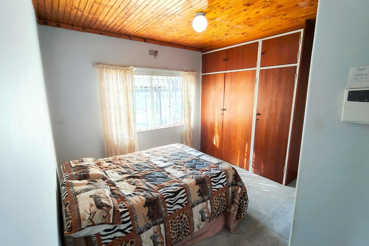 A bedroom featuring built-in wooden cupboards and a traditional wooden tongue and groove ceiling.