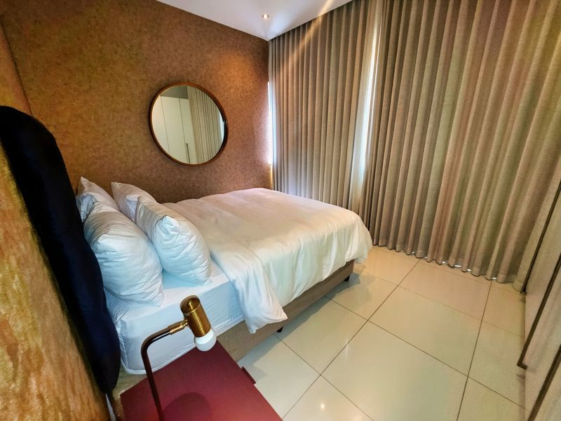 A modern bedroom featuring tiled flooring, built-in wardrobes, and floor-to-ceiling curtains, creating a comfortable and well-finished living space.