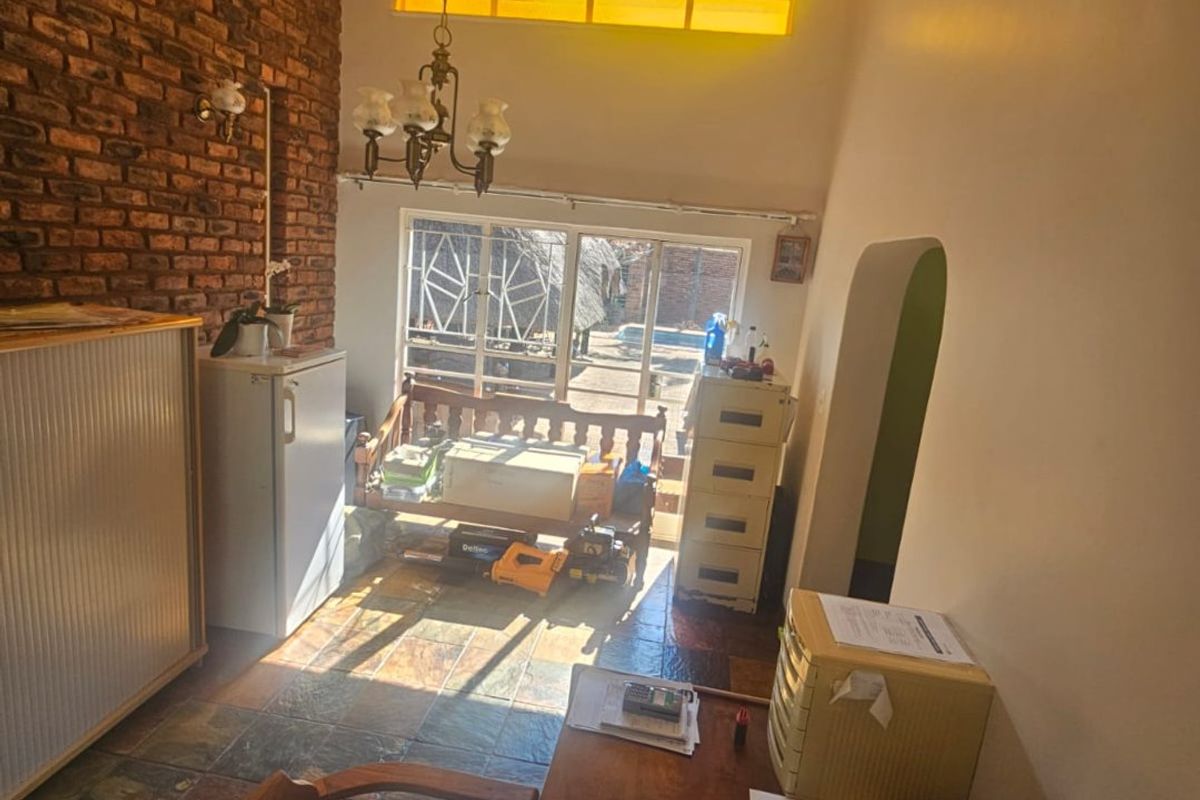 Living area featuring an exposed brick feature wall, slate tile flooring, and high ceilings with a clerestory window providing natural light.