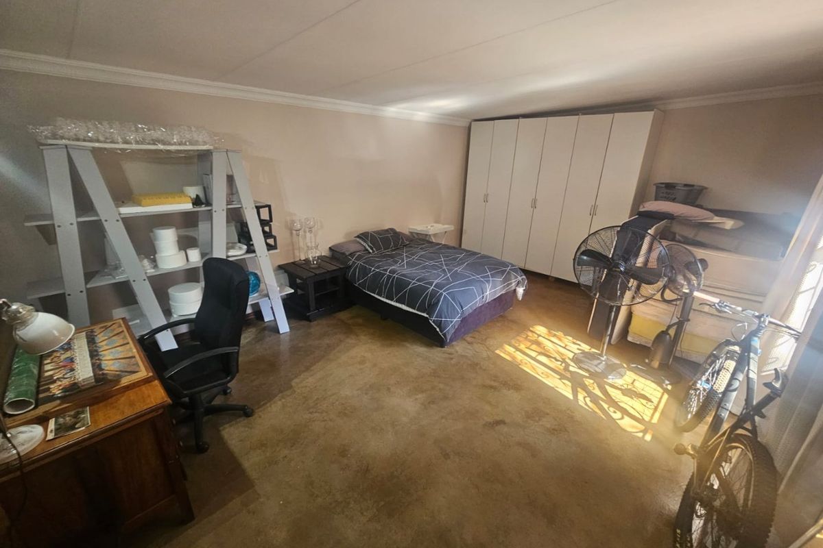 Spacious bedroom featuring polished concrete flooring, coved ceilings, and extensive built-in cupboard storage.
