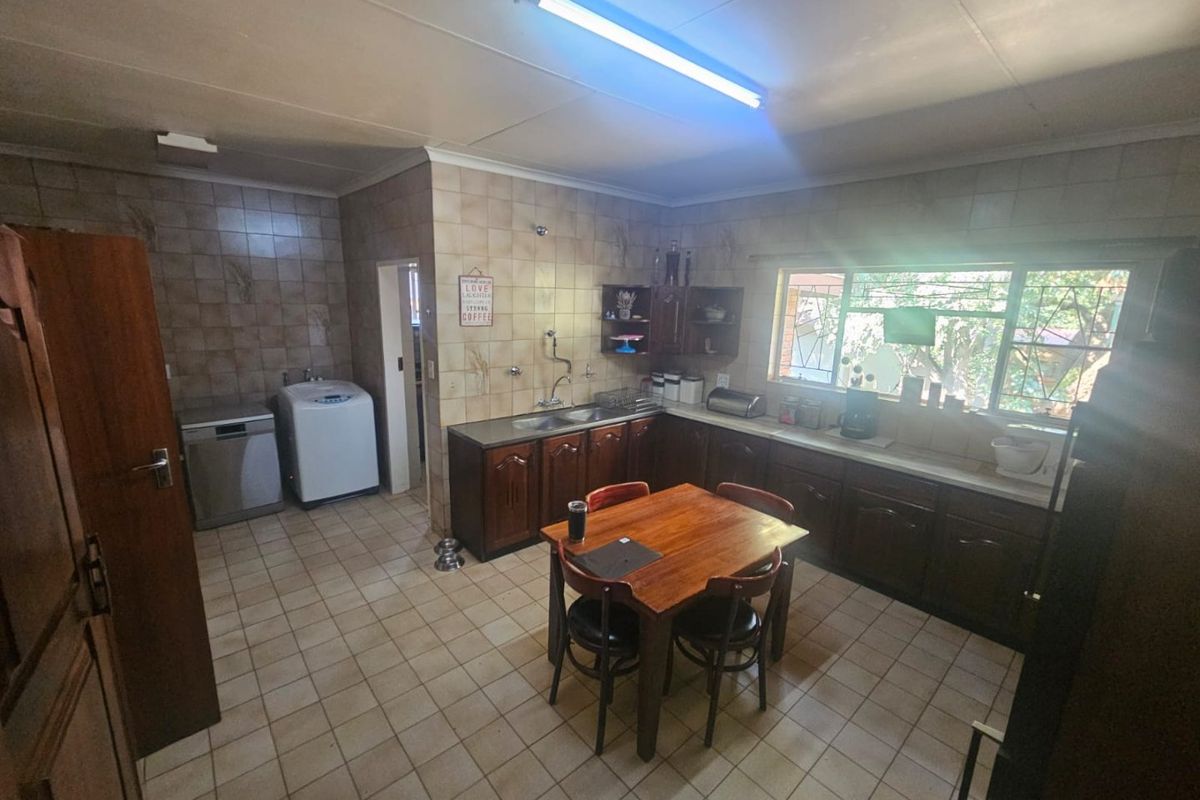 A functional kitchen featuring dark wood cabinetry, tiled splashbacks, and tiled flooring, offering a practical layout with integrated sink and laundry area access.