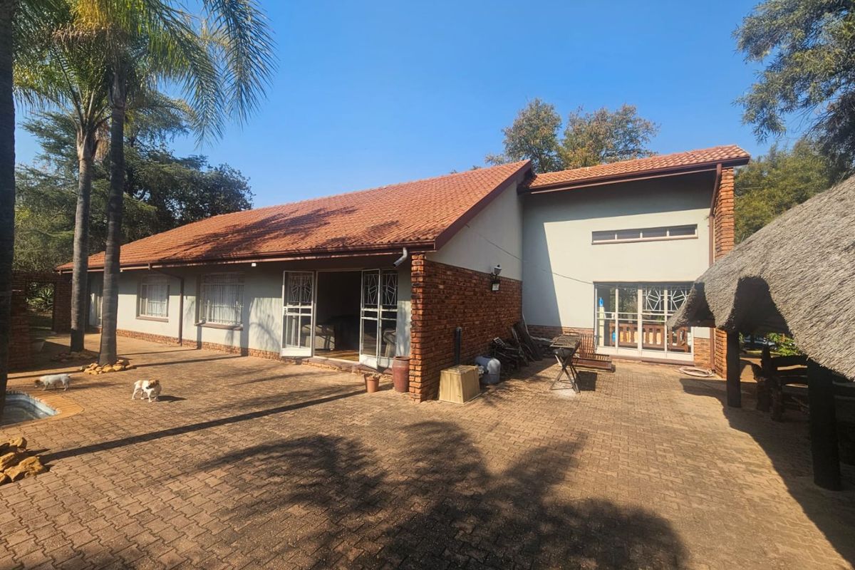 Rear view of the farm property featuring a spacious paved patio area, brick and plaster exterior walls, and a traditional terracotta tiled roof.