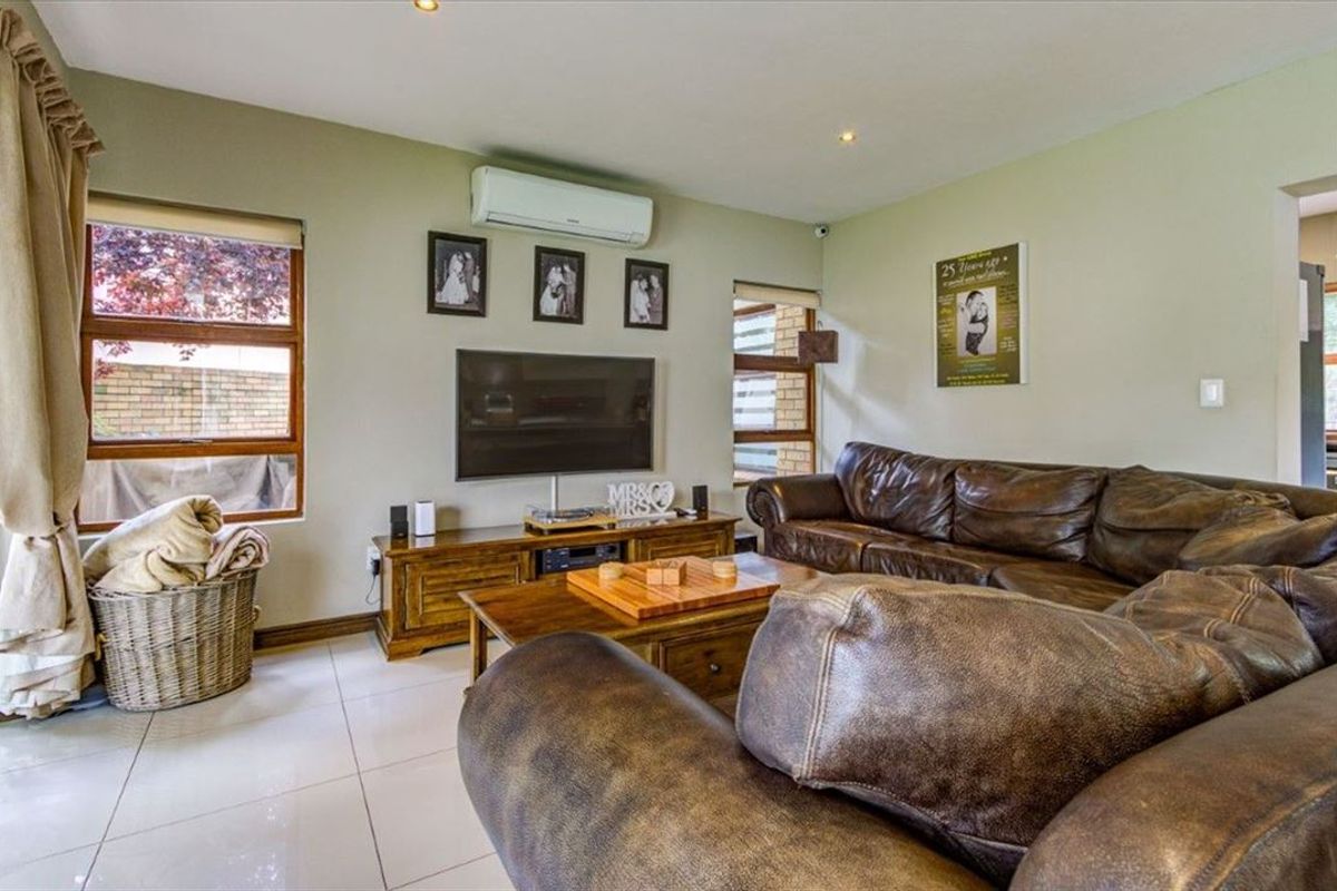 A comfortable living room featuring tiled flooring, recessed downlighting, and a wall-mounted split-system air conditioner for climate control.