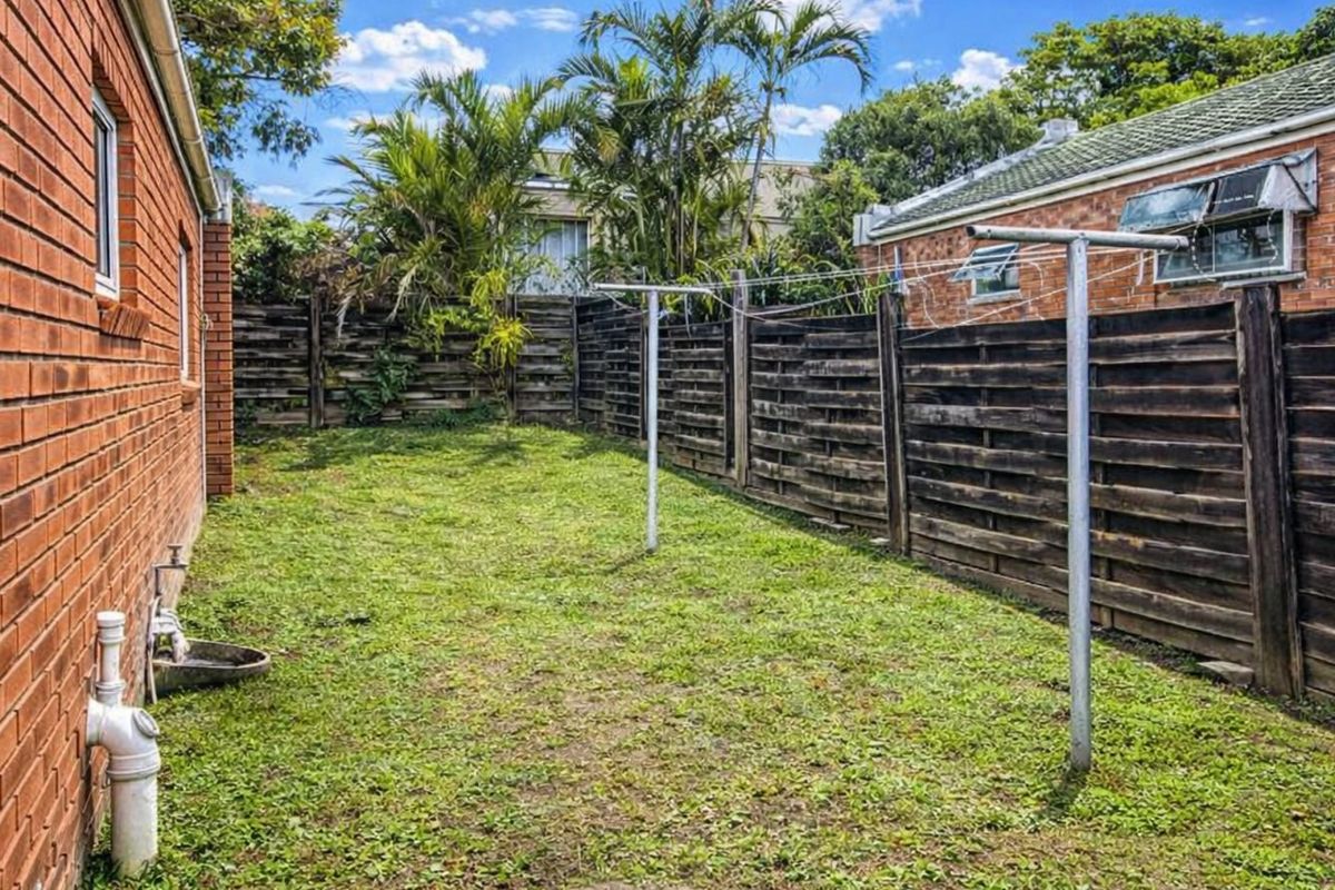 A private rear garden area featuring a brick exterior wall, timber boundary fencing, and a functional clothesline.
