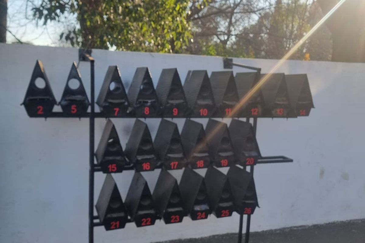 A bank of numbered metal mailboxes mounted on a support frame against an exterior wall.
