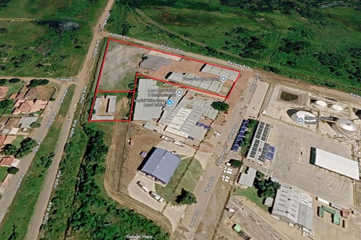 Aerial view of an industrial property featuring multiple warehouse buildings, a fenced yard, and direct access to surrounding street infrastructure.