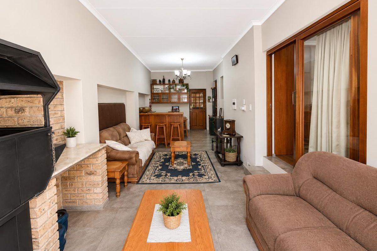 Spacious living area featuring a built-in fireplace with brick hearth, tiled flooring, and a dedicated bar area, providing a versatile space for relaxation and entertainment.