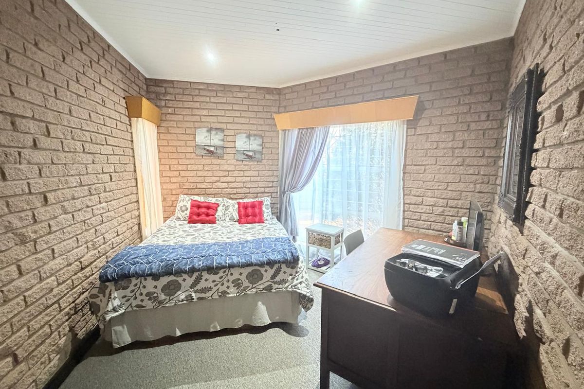 A bedroom featuring exposed brick walls, a tongue and groove ceiling, and a sliding glass door providing natural light.