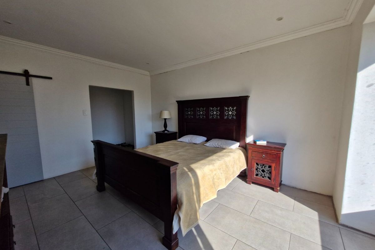 Spacious bedroom featuring neutral tiled flooring, recessed ceiling lighting, and a sliding barn door leading to a walk-in closet area.