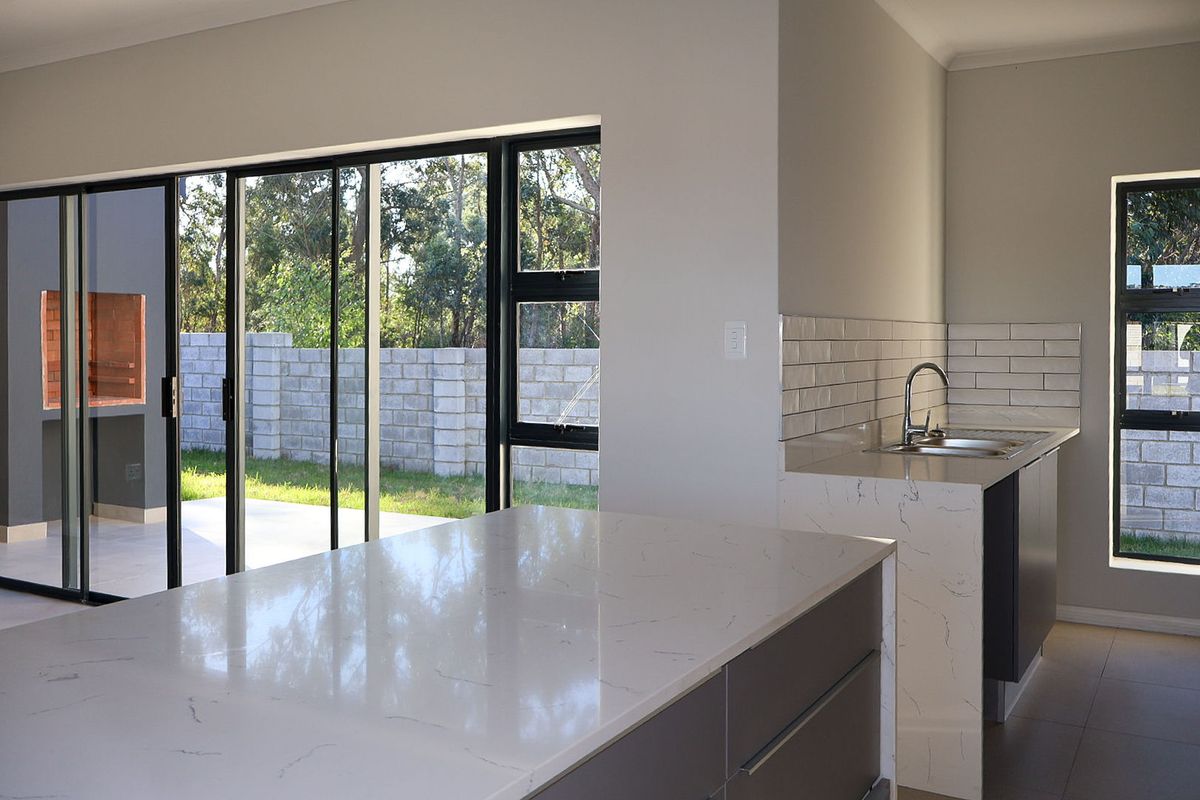 Modern kitchen featuring a stone island, subway tile backsplash, and large sliding glass doors opening to an outdoor patio area.