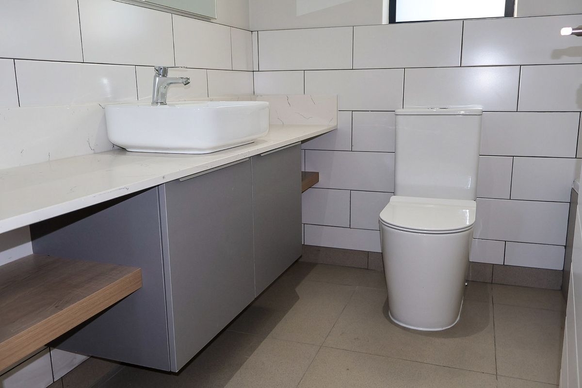 Modern bathroom featuring a vessel sink on a stone vanity, wall-mounted cabinetry, and clean subway tile finishes.