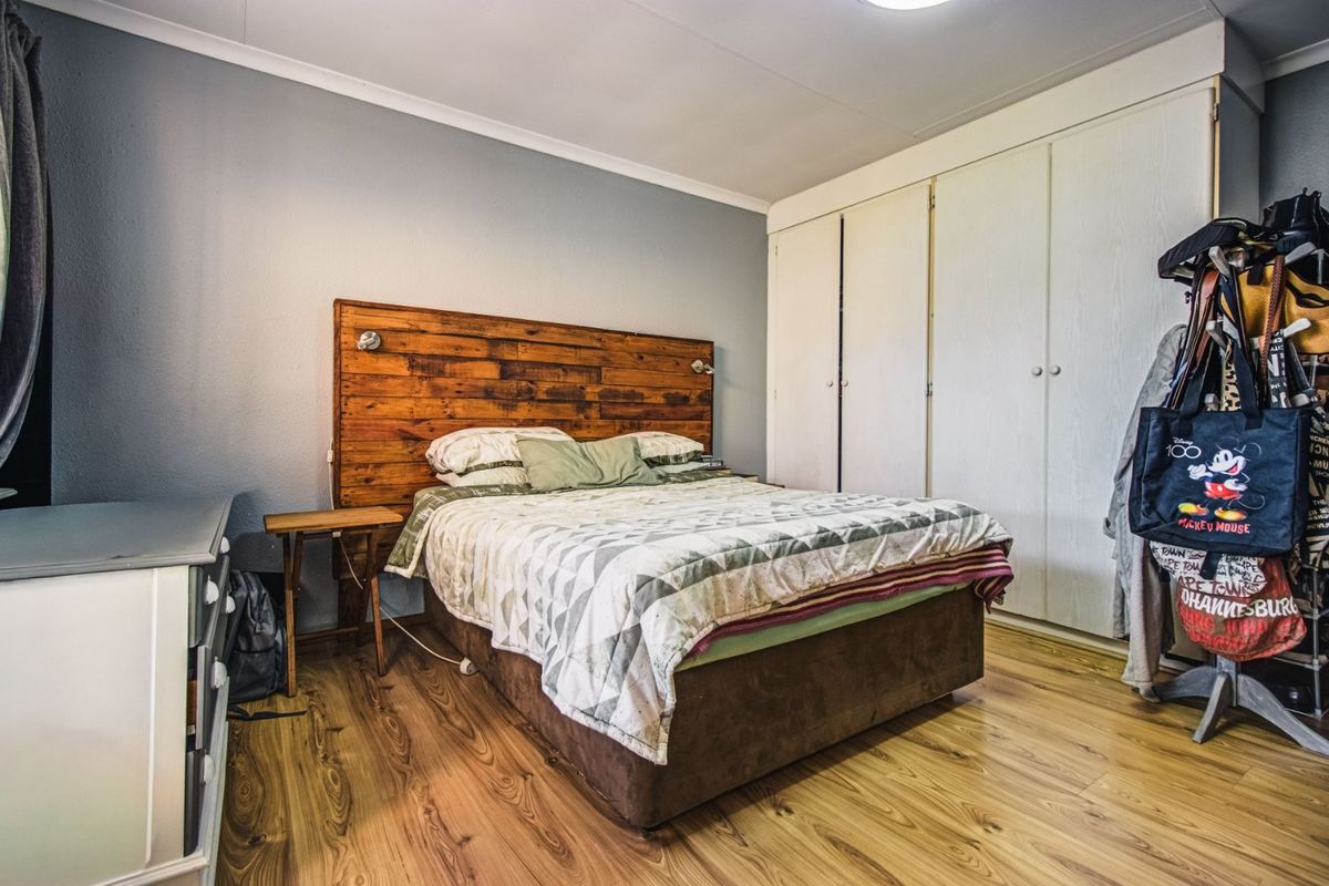A bedroom featuring laminate flooring and built-in cupboards, providing functional storage space.