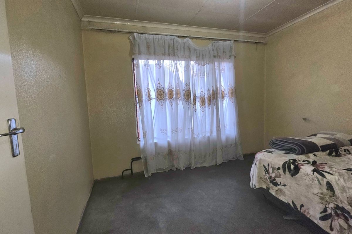 A bedroom featuring a window with a curtain rail and standard door hardware, requiring cosmetic updates to improve the overall finish.
