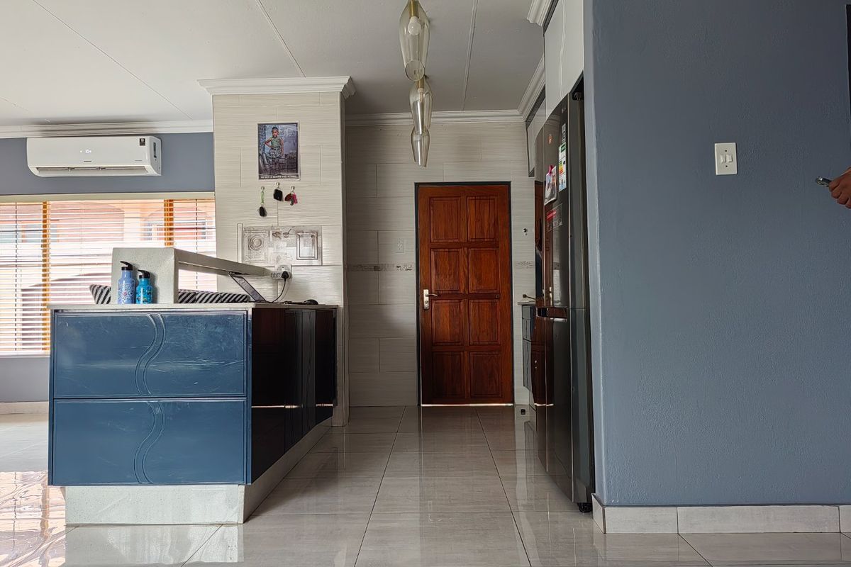 A modern kitchen area featuring a central island, tiled flooring, and contemporary pendant lighting, with a split system air conditioner for climate control.