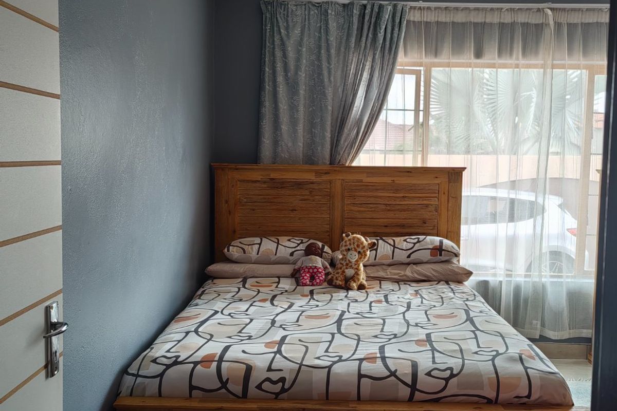 A bedroom featuring tiled flooring, neutral wall paint, and natural light through a window with curtain fixtures.