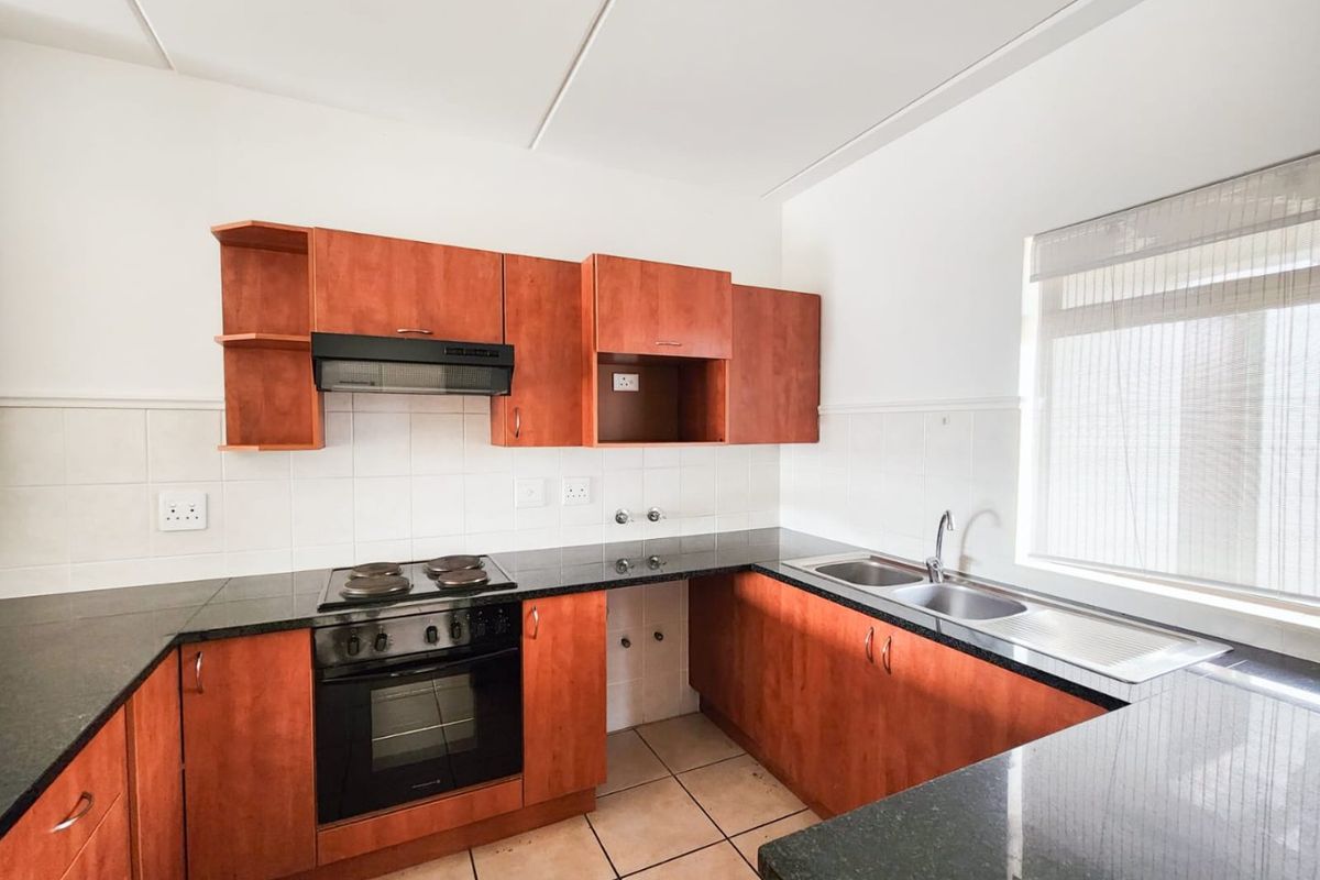 A functional kitchen featuring wooden cabinetry, granite countertops, a built-in oven and stove, and a double sink with tiled backsplash.