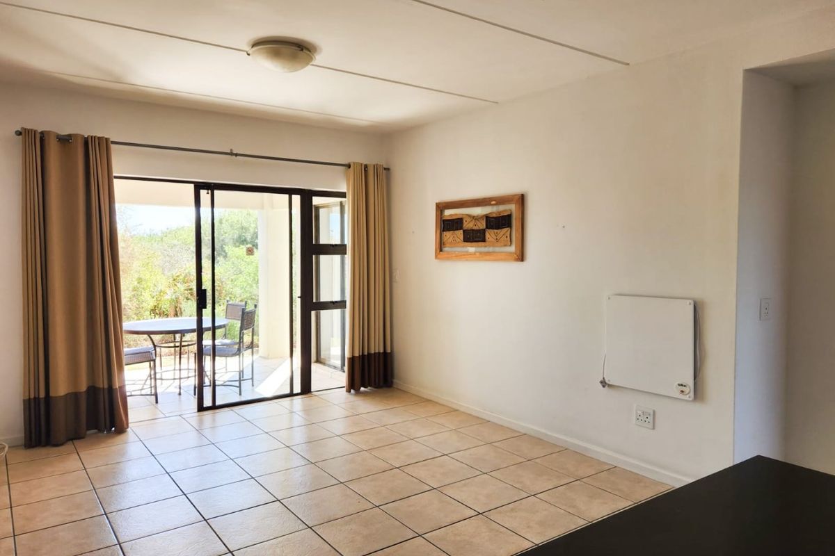 A bright living room featuring tiled flooring and a sliding glass door providing access to an outdoor patio area.