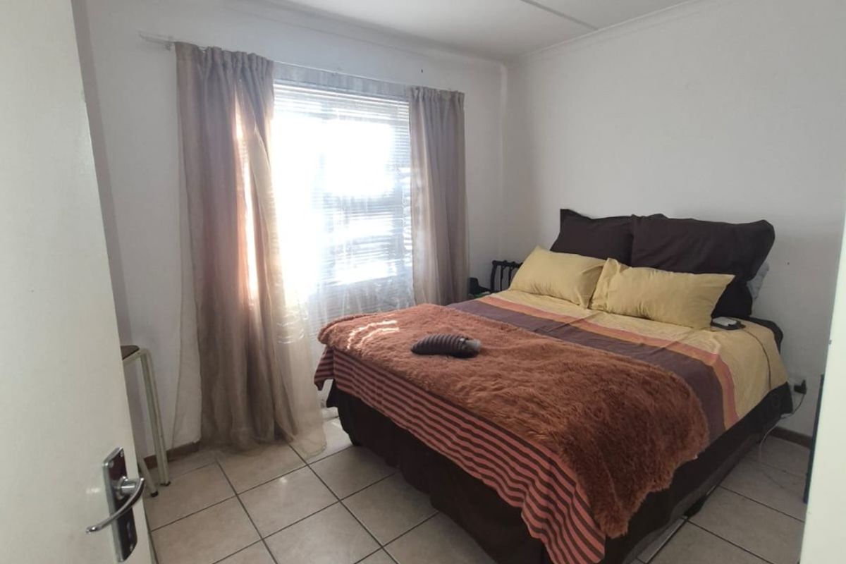 A functional bedroom featuring tiled flooring and a central ceiling light fixture, offering a neutral base for potential interior updates.