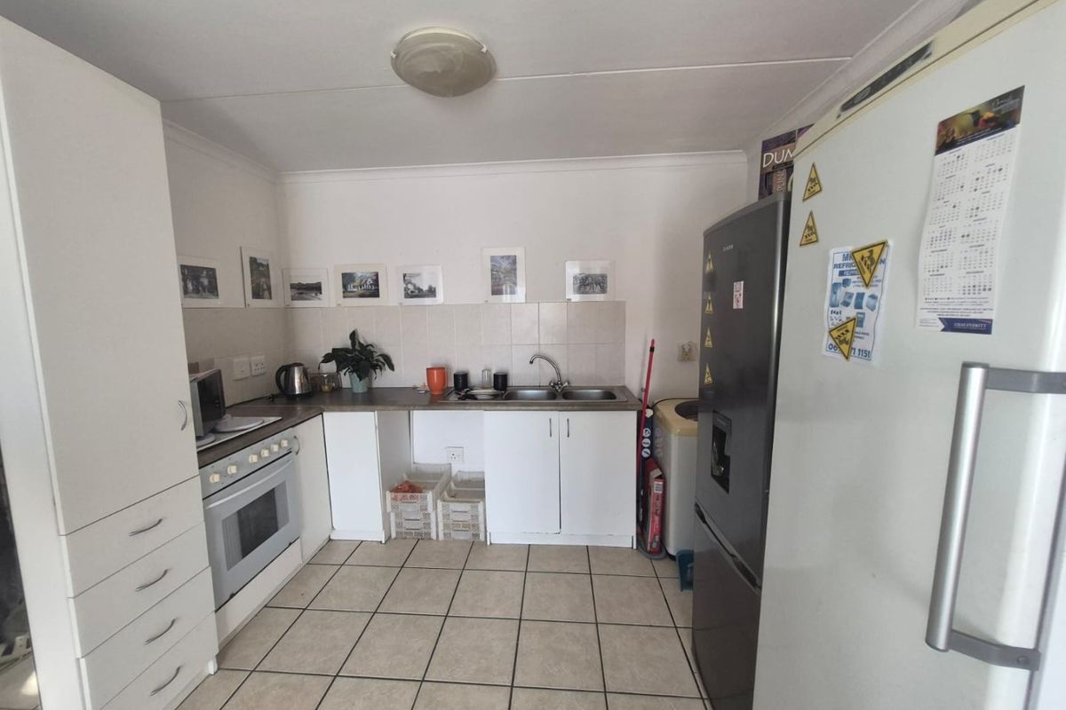 A functional kitchen featuring tiled flooring, built-in cabinetry, a stainless steel sink, and a built-in oven with a tiled backsplash.