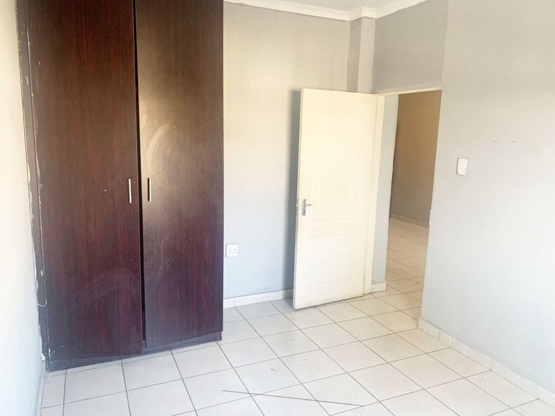 An empty bedroom featuring tiled flooring and a built-in wardrobe, providing a blank canvas for personalization.