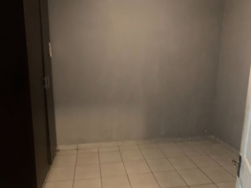 An empty bedroom featuring tiled flooring and a built-in cupboard, requiring minor cosmetic updates to the wall finishes.