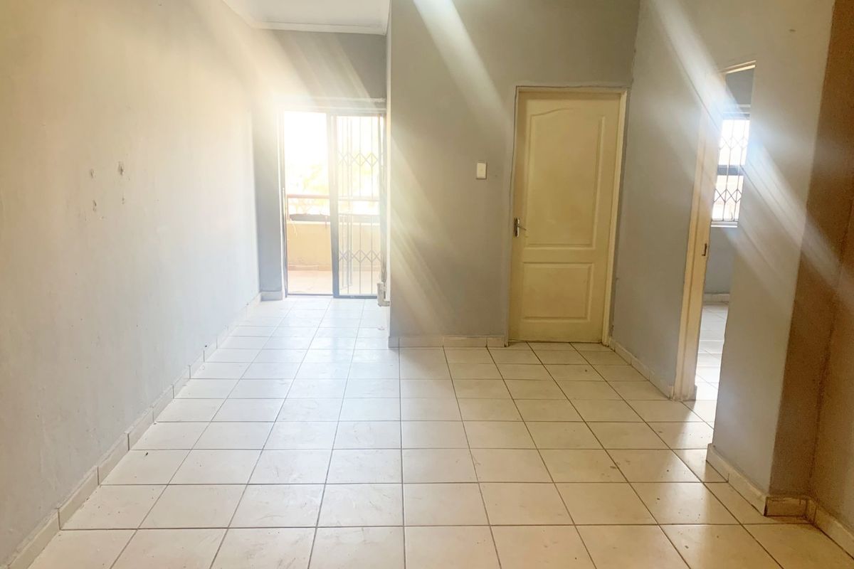 An empty living area featuring tiled flooring, neutral wall paint, and a sliding glass door leading to an outdoor space.