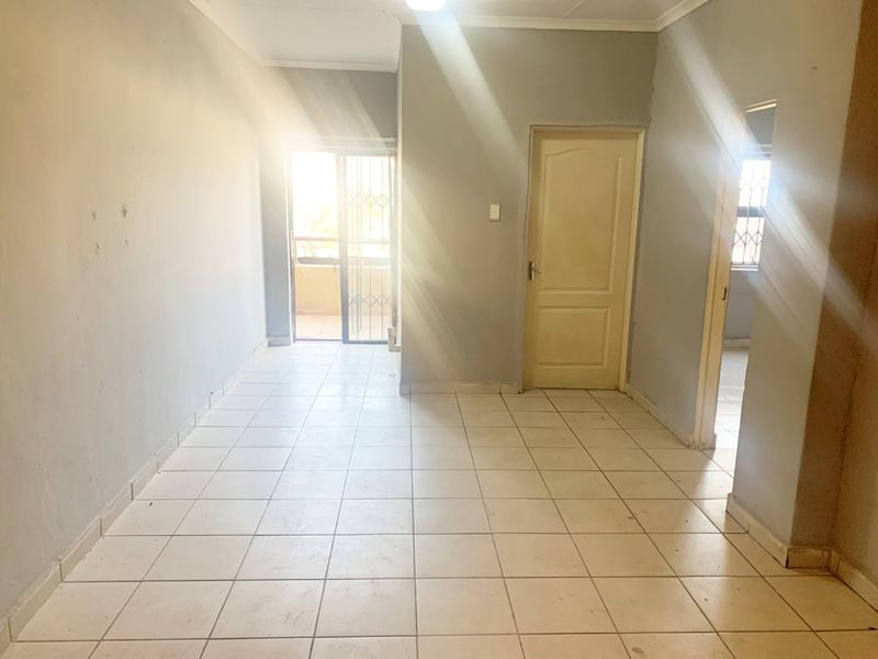An empty living area featuring tiled flooring, neutral wall paint, and a sliding glass door leading to an outdoor space.