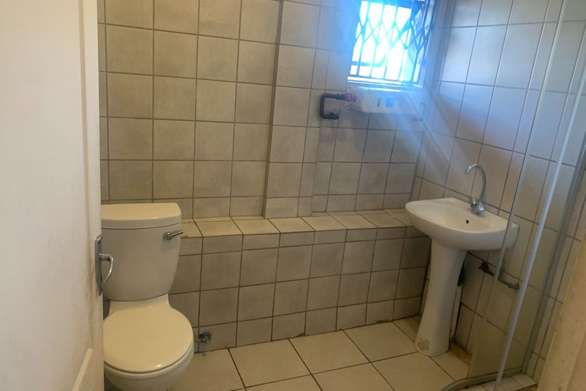 A functional bathroom featuring a pedestal basin, toilet, and tiled finishes, requiring some cosmetic updates to improve its overall condition and appeal.
