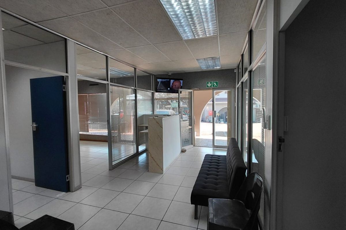 Commercial reception area featuring glass partitions, ceramic tiled flooring, and a built-in reception desk, providing a functional entry space for clients.