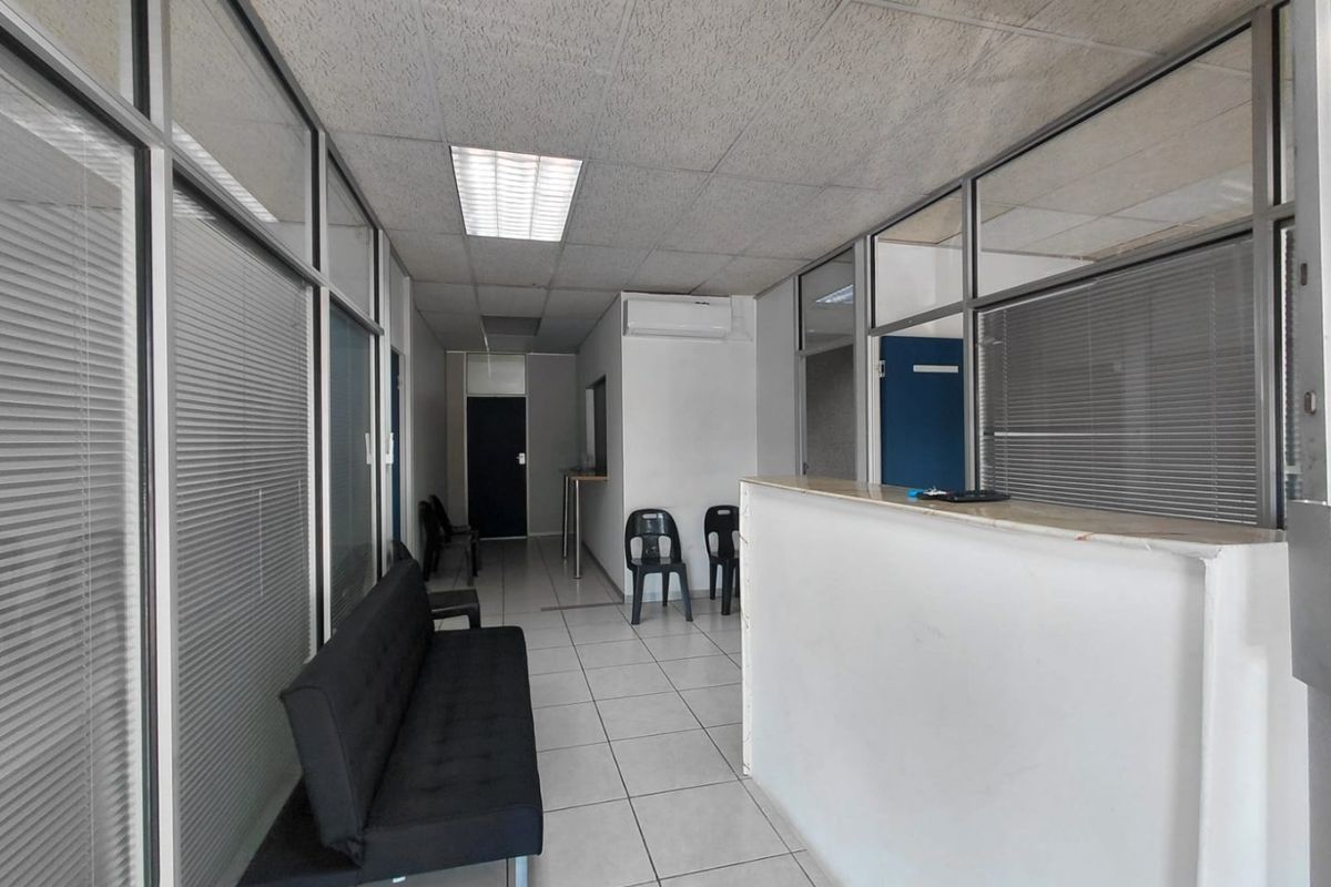 Commercial office reception area featuring aluminum-framed glass partitions, tiled flooring, and a built-in reception desk with integrated air conditioning.