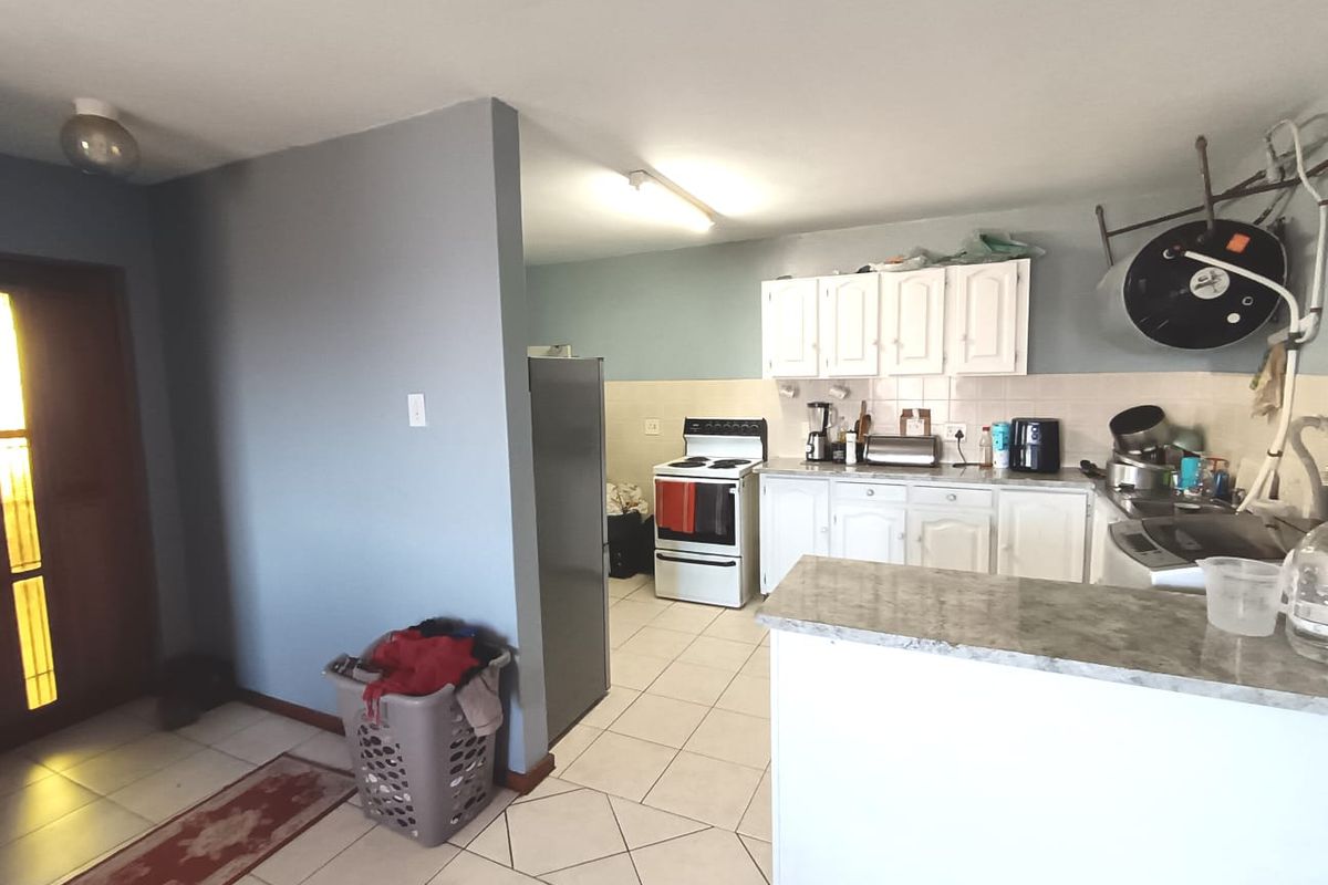 A functional kitchen area featuring white cabinetry, tiled backsplash, and an electric stove, with an open-plan layout connecting to the entrance area.