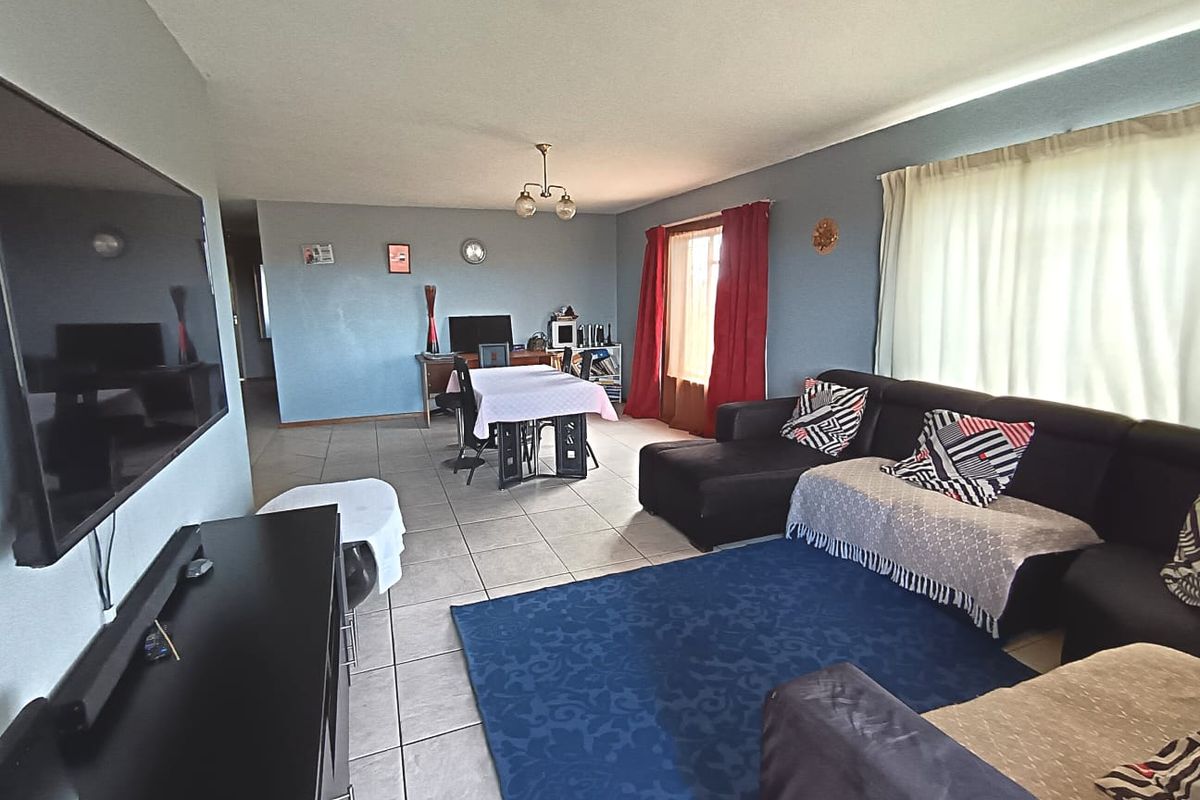 Spacious open-plan living area featuring neutral tiled flooring and ample natural light, providing a versatile space for relaxation and dining.