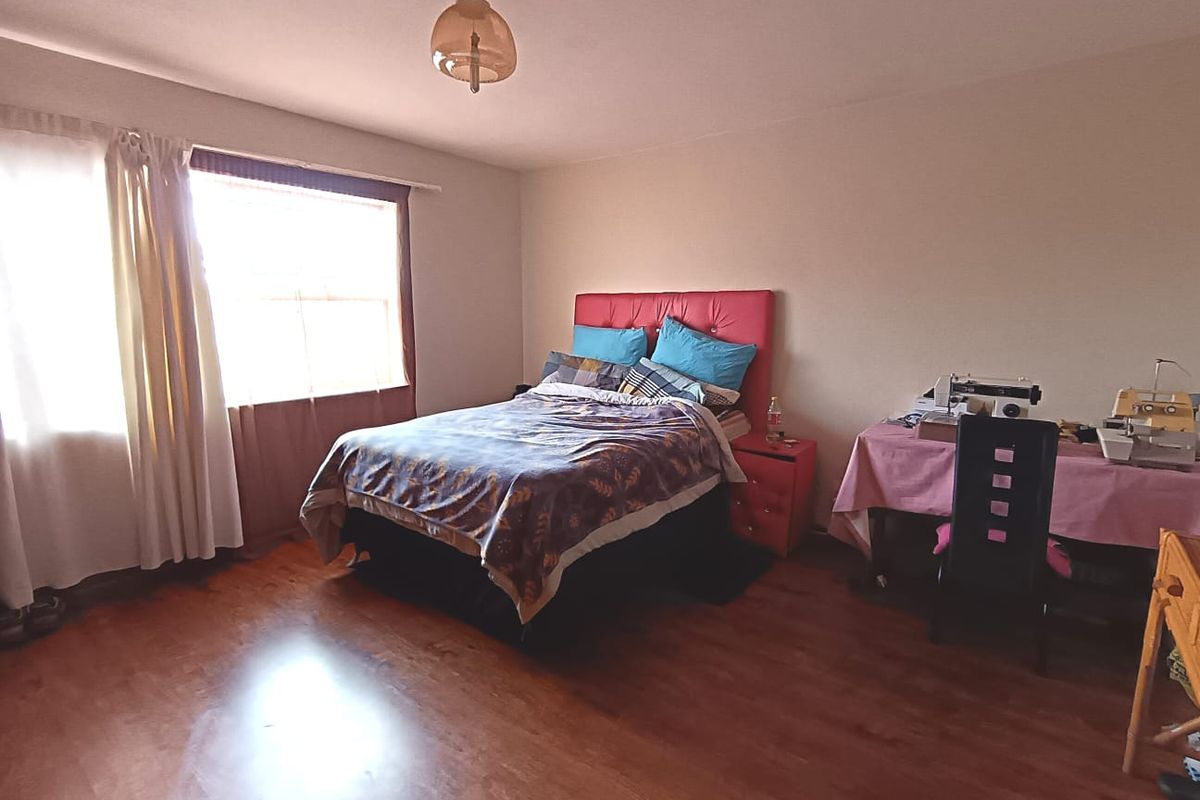 A spacious bedroom featuring laminate flooring and a central ceiling light fixture, offering a functional layout with ample natural light.