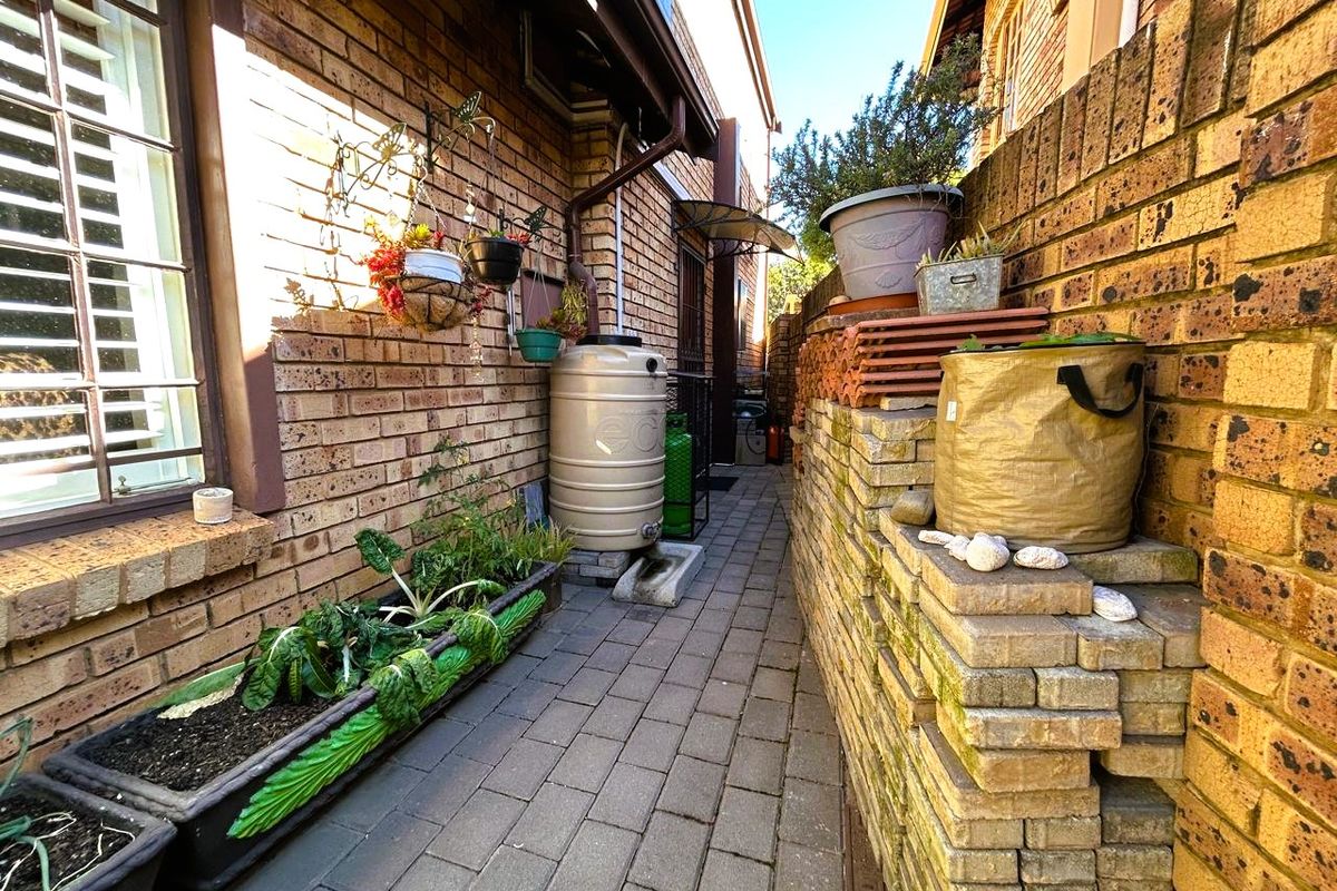 A narrow side passage featuring face brick walls, paved flooring, and a water storage tank.