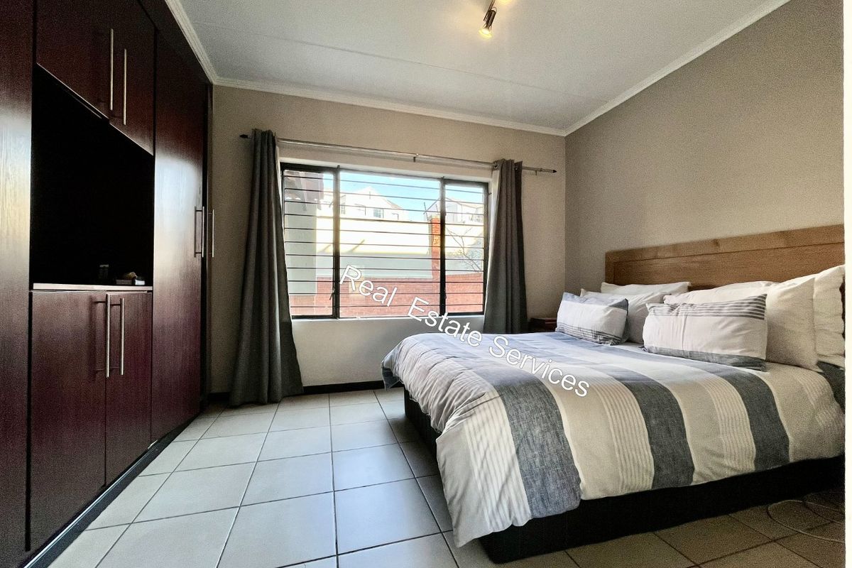 A bedroom featuring tiled flooring, a built-in wardrobe, and a window with security bars.