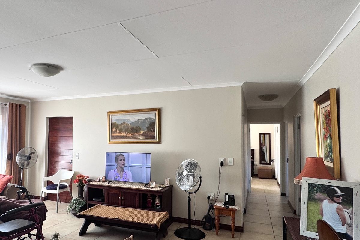 A spacious living room featuring neutral wall tones, tiled flooring, and coved ceilings, providing a functional and well-lit area for relaxation.