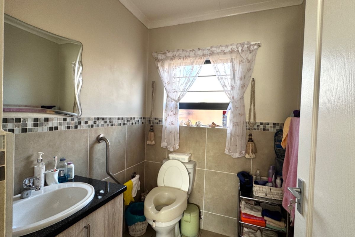 A functional bathroom featuring a vanity with granite countertop, mosaic tile accents, and a wall-mounted grab bar for accessibility.