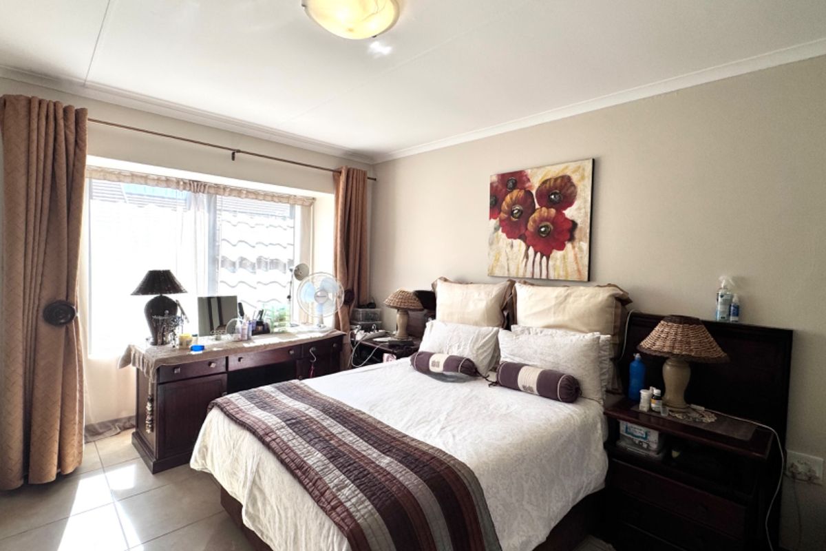 A well-lit bedroom featuring tiled flooring, coved ceilings, and a large window providing natural light.