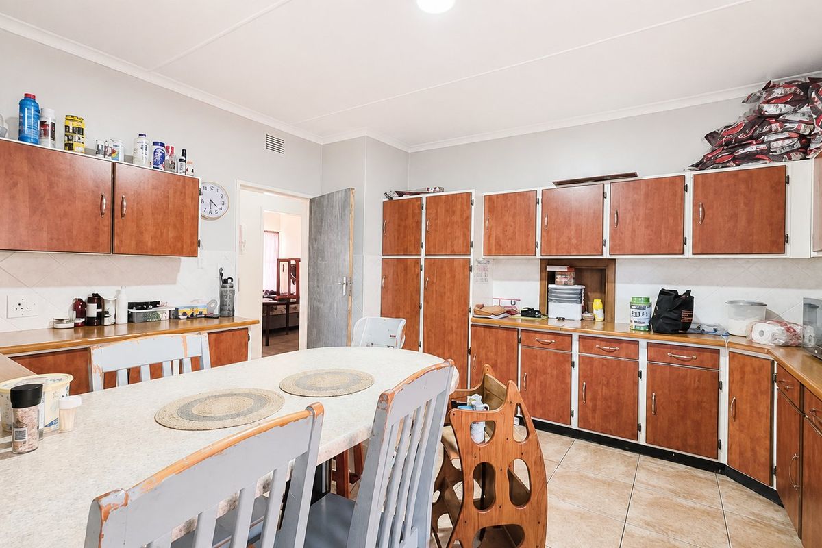 A functional kitchen featuring extensive laminate cabinetry, tiled flooring, and a tiled backsplash, offering ample storage and workspace for daily meal preparation.