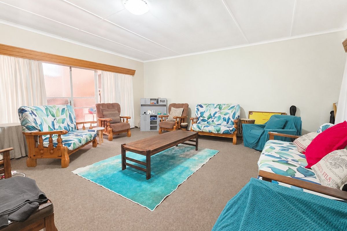 A spacious living room featuring neutral walls, carpeted flooring, and a large sliding glass door providing access to the exterior.