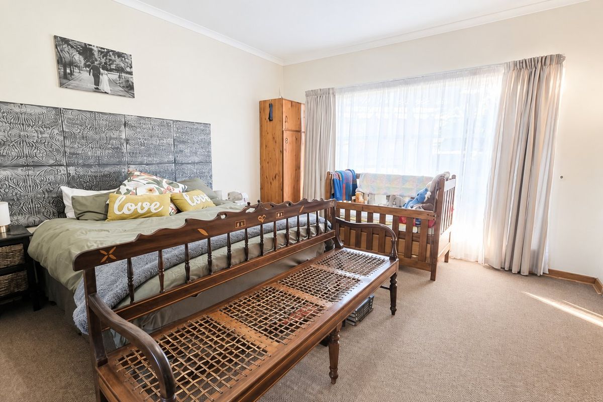 A spacious bedroom featuring neutral walls, carpeted flooring, and a built-in wardrobe, offering a comfortable and functional living space.
