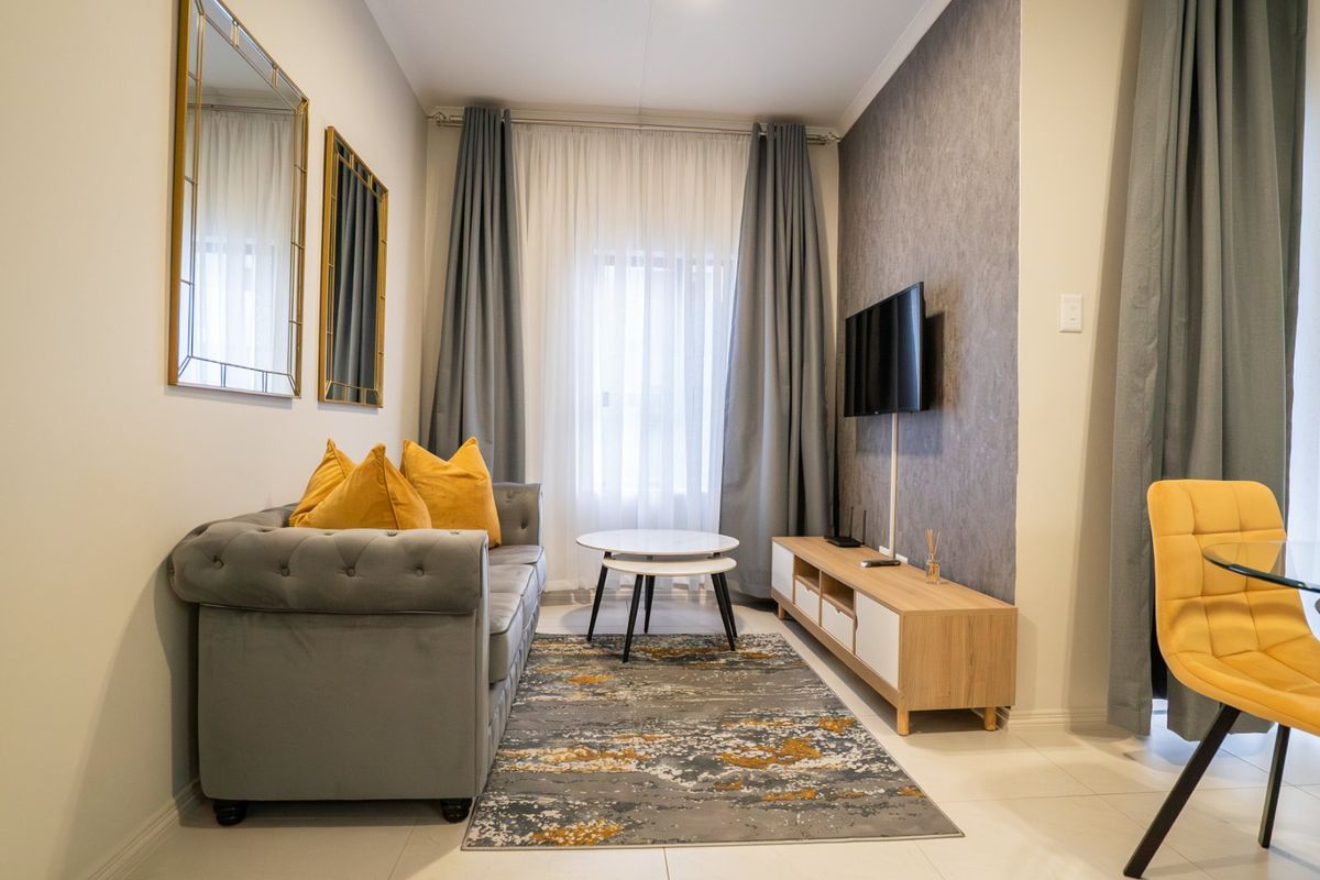 A well-maintained living room featuring tiled flooring, a textured accent wall, and neutral decor, creating a comfortable and inviting space.